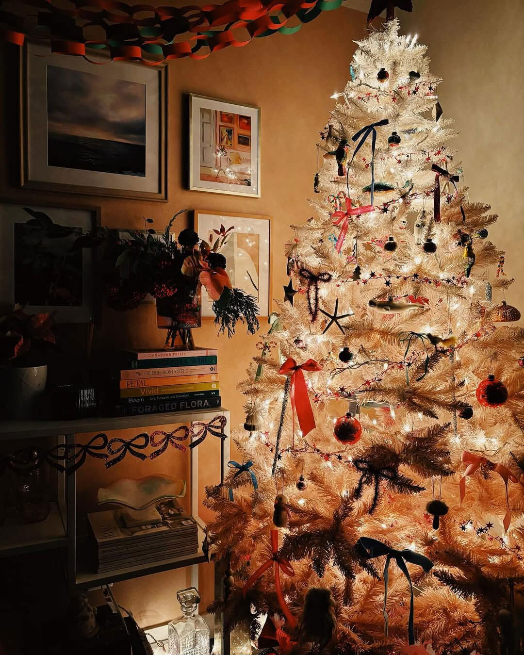 pink christmas tree in candle light with pink wall, picture frames, bow garland and paper chains by @studiowallflower