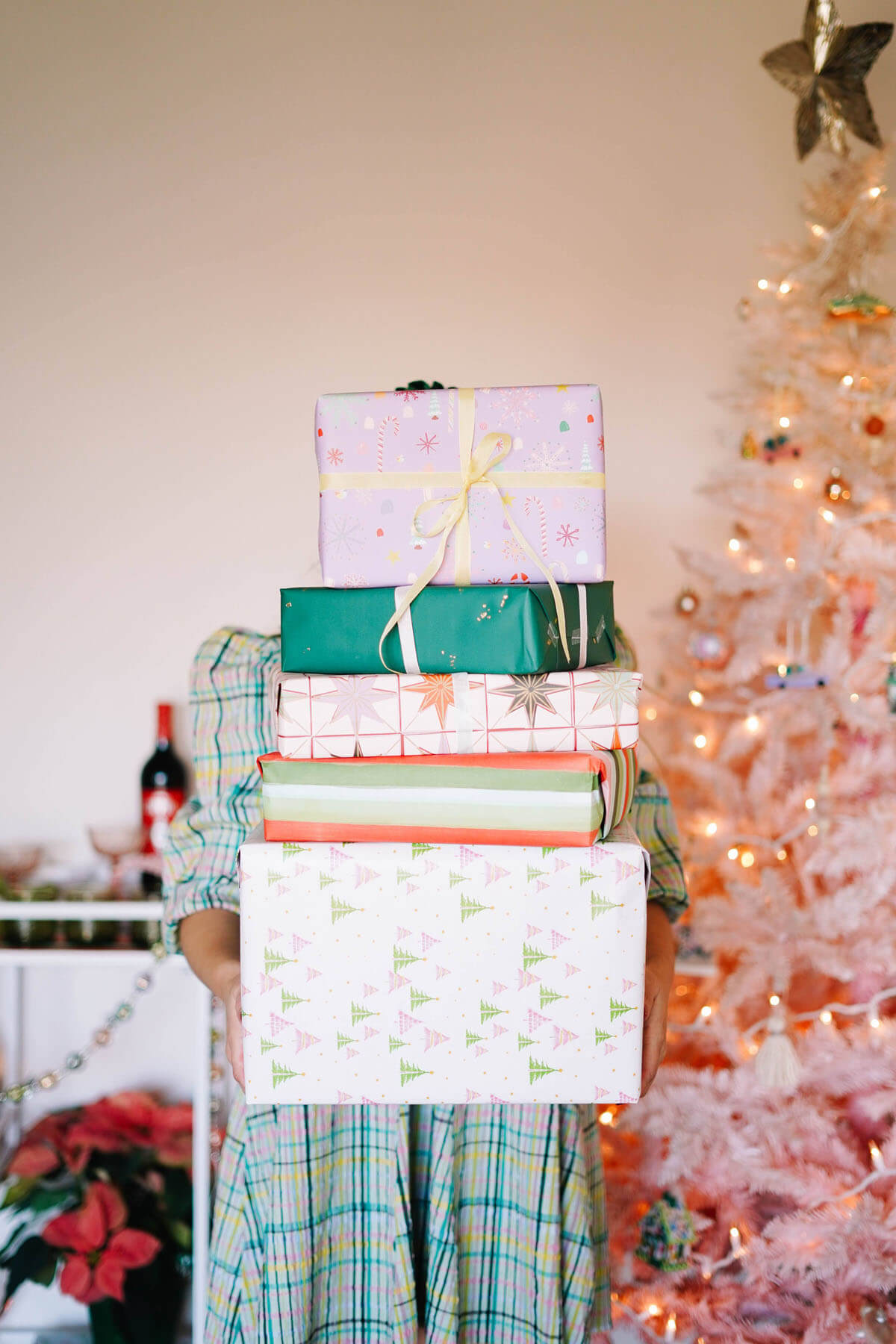 stack of presents in front of blush christmas tree